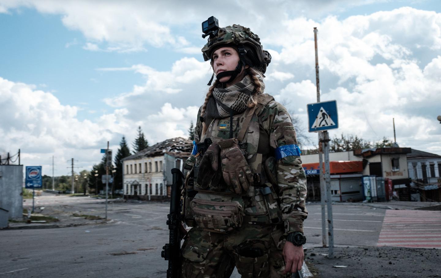 A soldier standing on a street in Ukraine amid damaged buildings